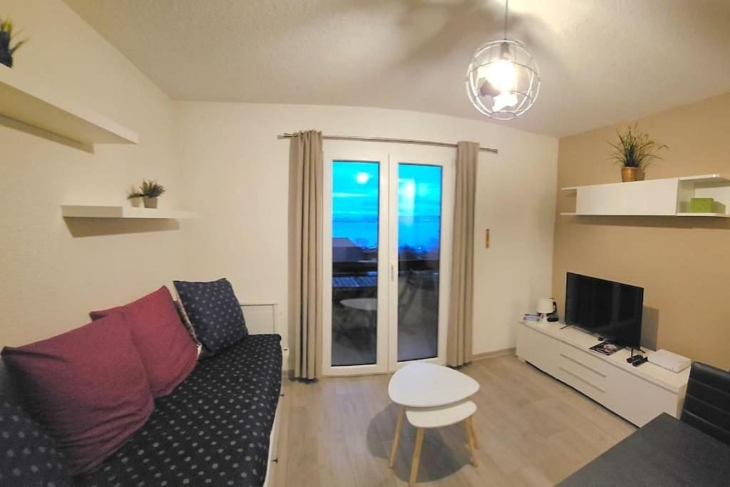 Le salon de l'appartement d'Évian, sa banquette-lit et la porte-fenêtre du balcon
